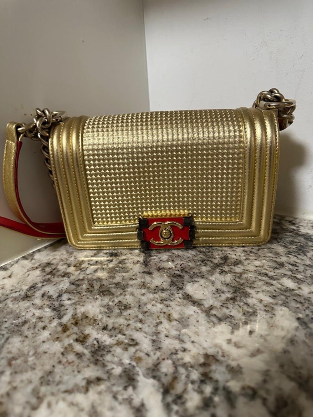 CHANEL Gold Shoulder Bag with Red Accent Strap (PREOWNED).